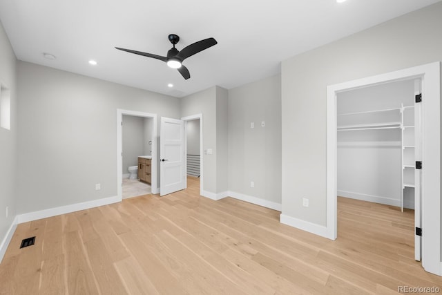 unfurnished bedroom with ensuite bathroom, light wood-type flooring, a closet, and a spacious closet