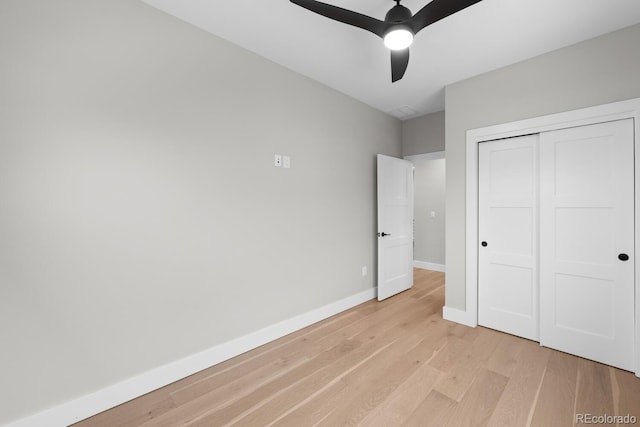 unfurnished bedroom with ceiling fan, light wood-type flooring, and a closet