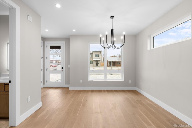 unfurnished dining area featuring light hardwood / wood-style floors and a chandelier