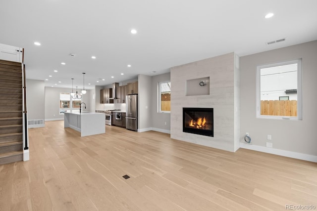 unfurnished living room featuring light wood-type flooring, a fireplace, plenty of natural light, and a barn door