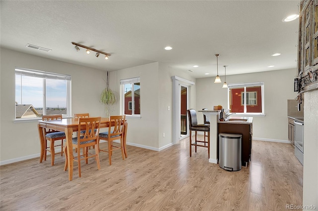 dining area with sink, light hardwood / wood-style flooring, and a textured ceiling