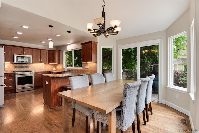 11056 W Rowland Ave, Littleton, CO 80127 - dining area featuring plenty of natural light, light wood finished floors, a chandelier, recessed lighting, and baseboards