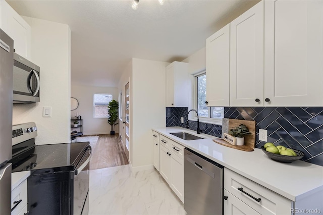 kitchen featuring tasteful backsplash, stainless steel appliances, sink, and white cabinets