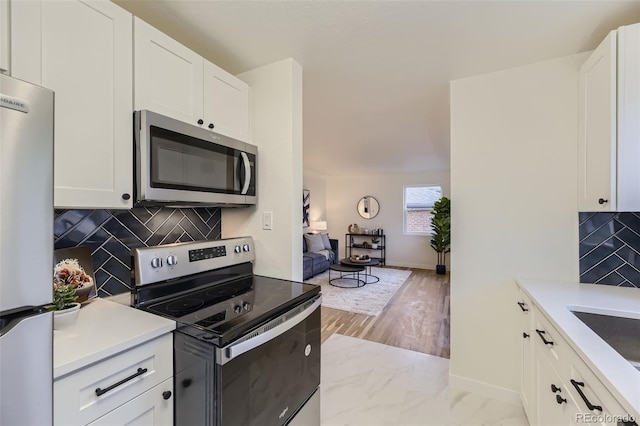 kitchen featuring sink, white cabinetry, stainless steel appliances, tasteful backsplash, and light hardwood / wood-style floors