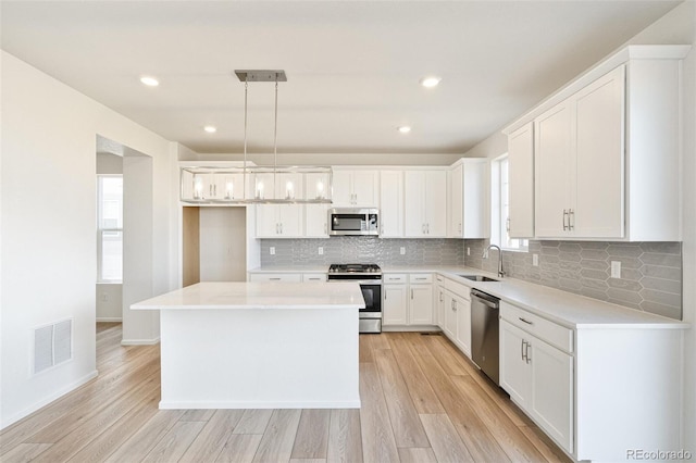 kitchen with sink, pendant lighting, white cabinets, and stainless steel appliances