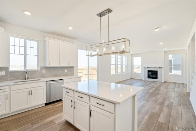 kitchen featuring dishwasher, light hardwood / wood-style flooring, hanging light fixtures, a center island, and white cabinetry