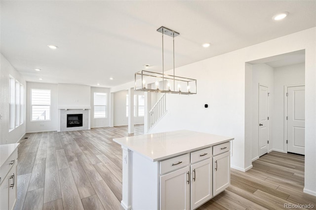 kitchen featuring white cabinetry, a center island, decorative light fixtures, and light wood-type flooring