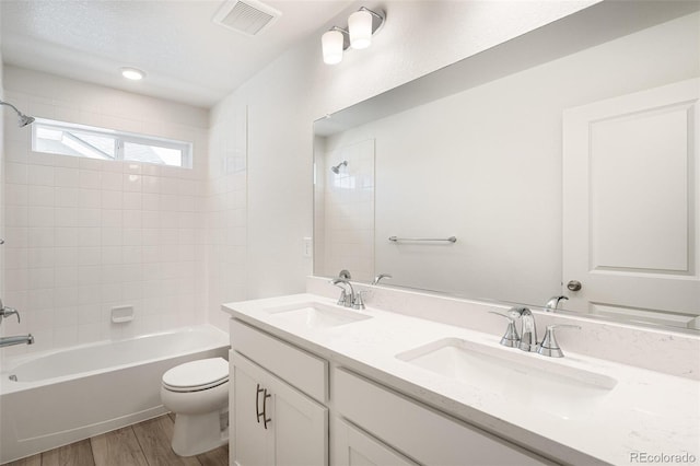 full bathroom featuring tiled shower / bath, a textured ceiling, hardwood / wood-style flooring, toilet, and vanity