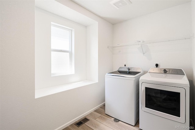 laundry room with light hardwood / wood-style flooring and washing machine and dryer