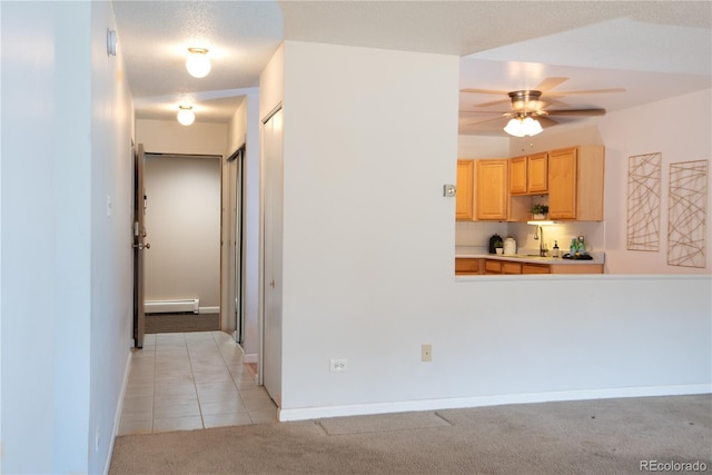 corridor with light tile patterned floors, a baseboard radiator, light colored carpet, a sink, and baseboards