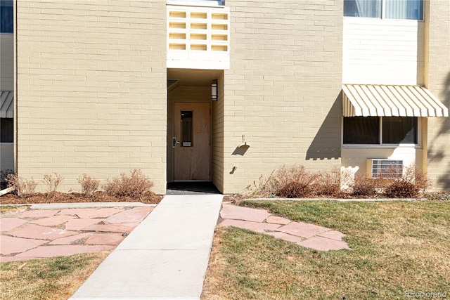 property entrance with brick siding and a yard