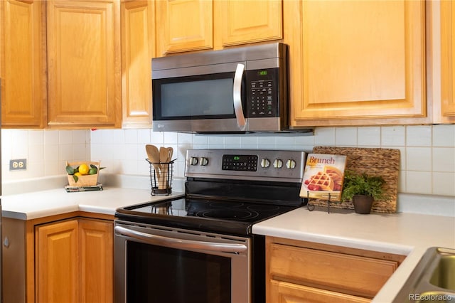 kitchen with stainless steel appliances, tasteful backsplash, and light countertops