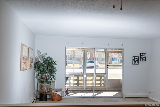 interior space with a baseboard heating unit, a textured ceiling, and baseboards