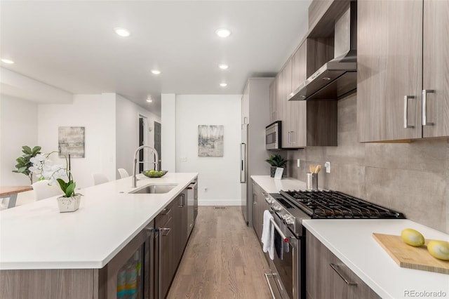3586 S Ogden St, Englewood, CO 80113 - kitchen featuring wall chimney range hood, stainless steel appliances, a kitchen island with sink, light countertops, and recessed lighting
