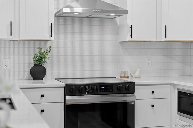3036 Wolff St S, Denver, CO 80236 - kitchen with appliances with stainless steel finishes, wall chimney exhaust hood, decorative backsplash, white cabinets, and light countertops