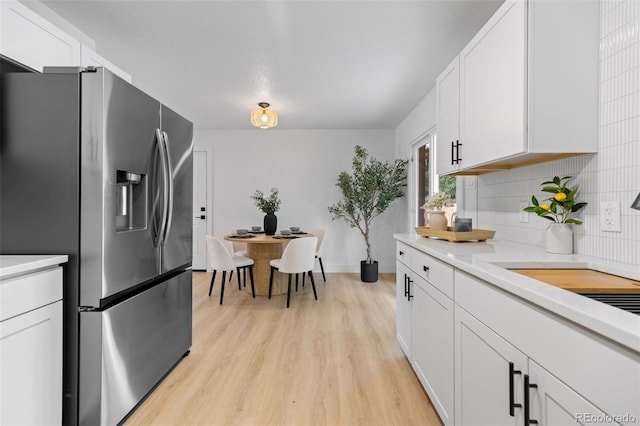 3036 Wolff St S, Denver, CO 80236 - kitchen featuring stainless steel refrigerator with ice dispenser, light wood-style flooring, light countertops, white cabinetry, and tasteful backsplash
