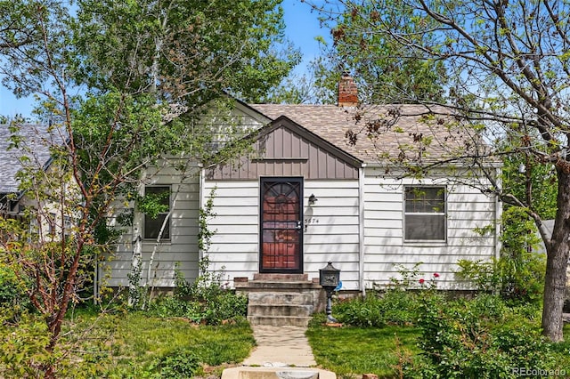 bungalow-style home featuring a chimney, board and batten siding, and a shingled roof