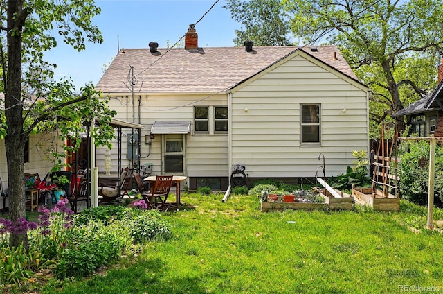 rear view of property featuring a garden, a shingled roof, and a chimney
