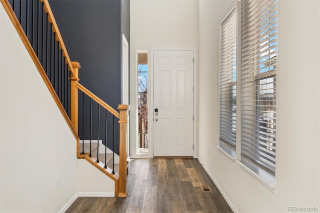 entryway with dark wood-type flooring, stairway, visible vents, and baseboards