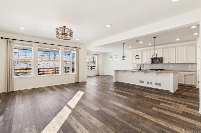 unfurnished living room featuring a sink, baseboards, dark wood finished floors, and recessed lighting