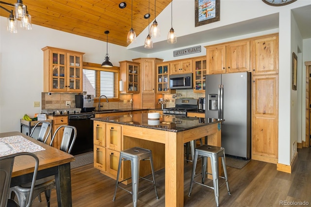 kitchen with a breakfast bar, stainless steel appliances, decorative backsplash, a sink, and wooden ceiling