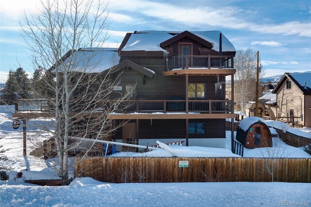 snow covered house featuring a balcony