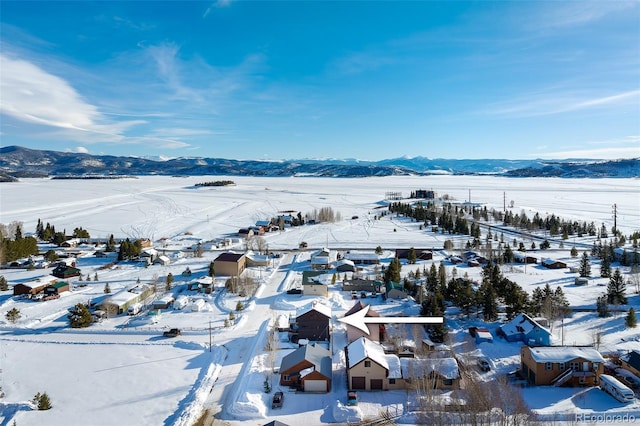 snowy aerial view featuring a residential view and a mountain view