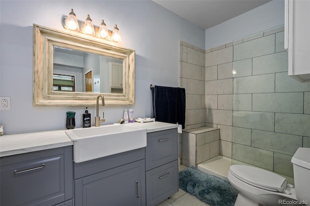 full bath featuring toilet, a tile shower, and vanity