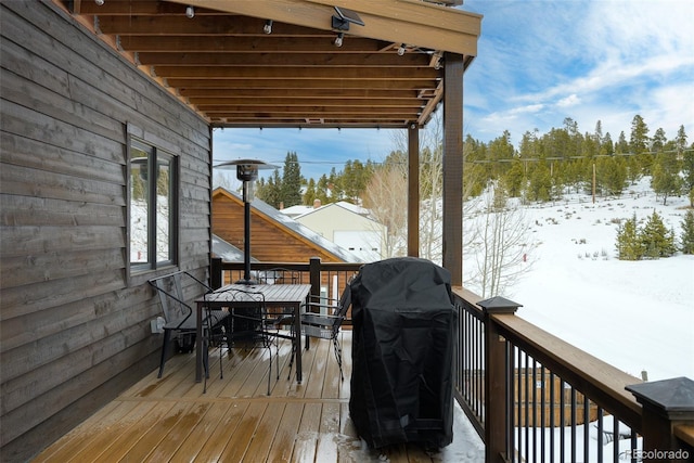 snow covered deck with a grill and outdoor dining space