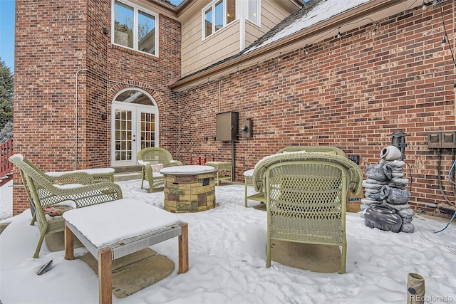 snow covered patio featuring an outdoor fire pit and french doors