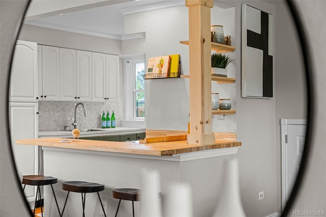 2867 Jasmine St, Denver, CO 80207 - kitchen with butcher block countertops, white cabinetry, a kitchen breakfast bar, backsplash, and ornamental molding