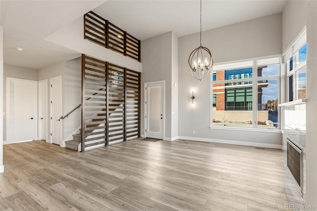 interior space with a towering ceiling, light wood-type flooring, and a notable chandelier