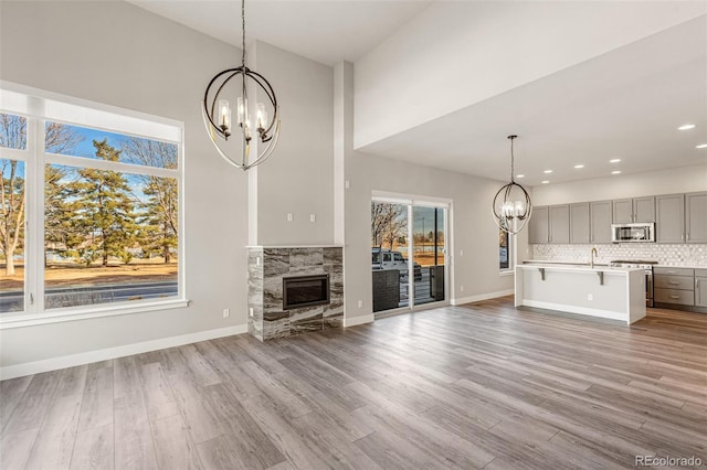 unfurnished living room featuring light hardwood / wood-style floors, sink, a fireplace, and a chandelier