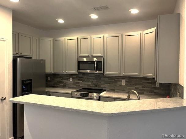 11282 Osage Cir N Unit F, Northglenn, CO 80234 - kitchen featuring stainless steel appliances, decorative backsplash, light stone countertops, a peninsula, and recessed lighting