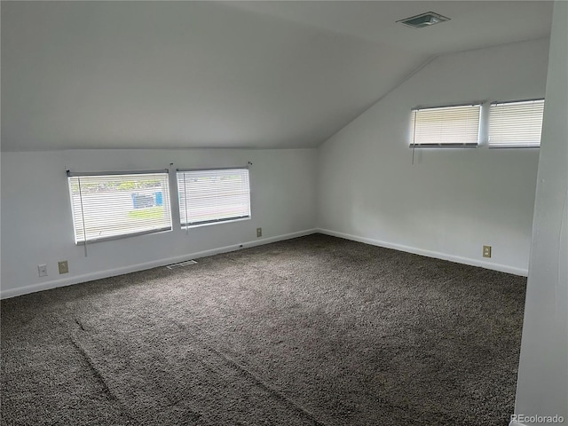 additional living space featuring vaulted ceiling and dark colored carpet