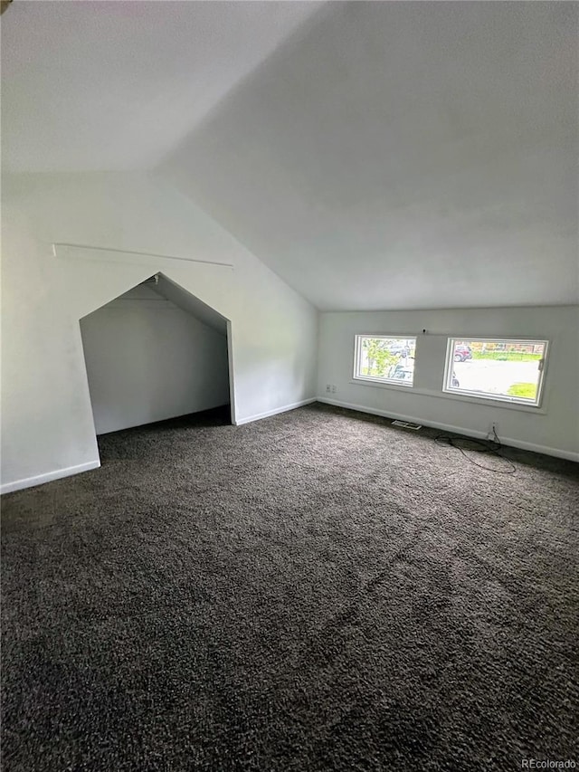 bonus room with lofted ceiling and dark carpet