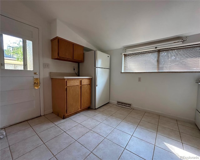 kitchen with white fridge, vaulted ceiling, and light tile patterned flooring