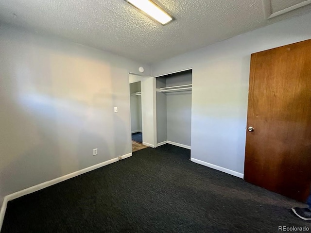 unfurnished bedroom featuring a closet, a textured ceiling, and dark colored carpet