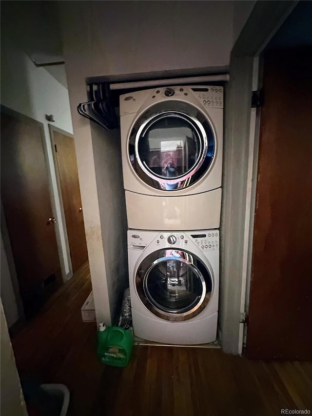 washroom featuring stacked washer / drying machine and dark hardwood / wood-style flooring