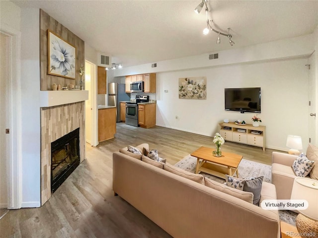 living room featuring a tiled fireplace and light hardwood / wood-style flooring