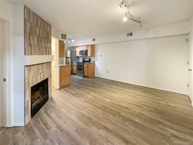 unfurnished living room with light hardwood / wood-style floors, a tile fireplace, and a textured ceiling