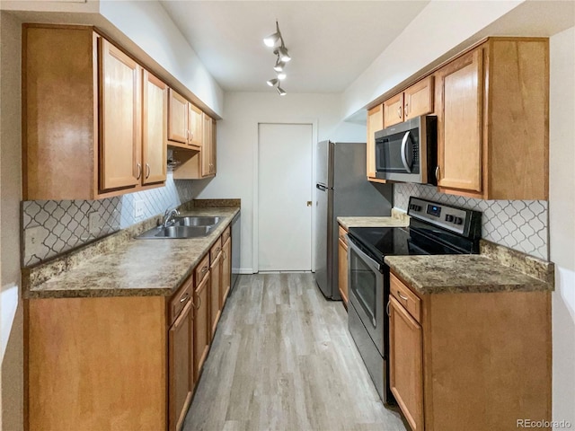 kitchen with decorative backsplash, appliances with stainless steel finishes, sink, and light hardwood / wood-style flooring