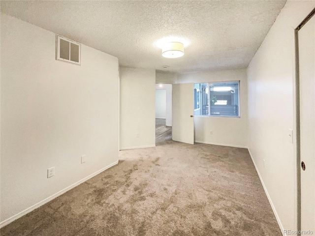 carpeted empty room featuring a textured ceiling