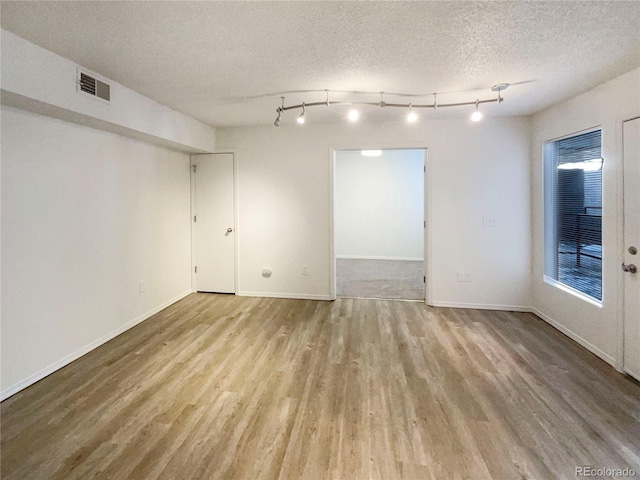 unfurnished room with light hardwood / wood-style floors and a textured ceiling