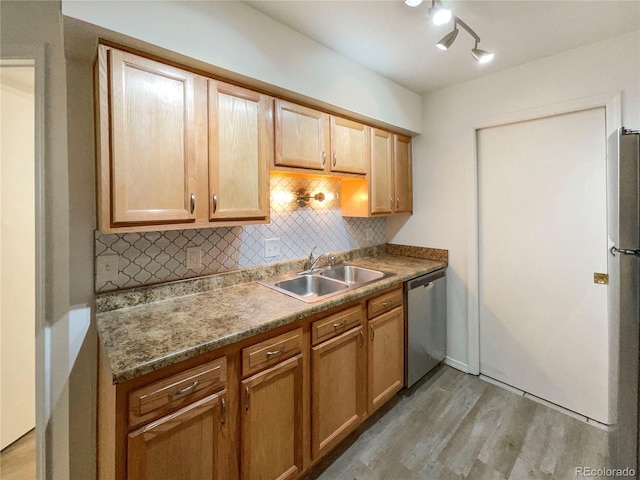 kitchen with dishwasher, sink, dark stone countertops, backsplash, and light wood-type flooring