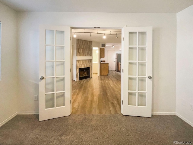 unfurnished room featuring french doors, a fireplace, and carpet