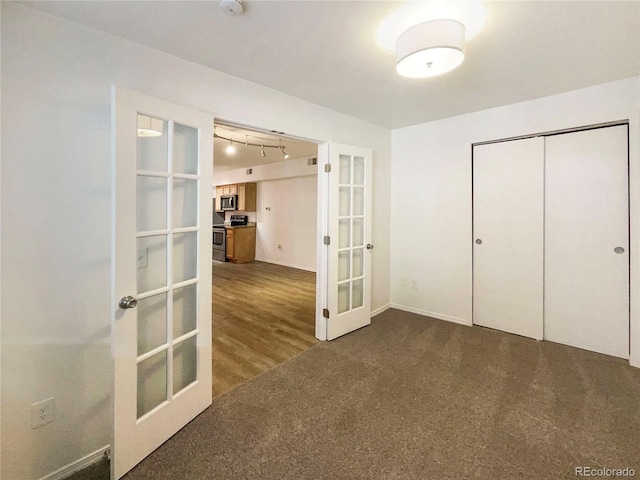 unfurnished bedroom with a closet, dark carpet, and french doors