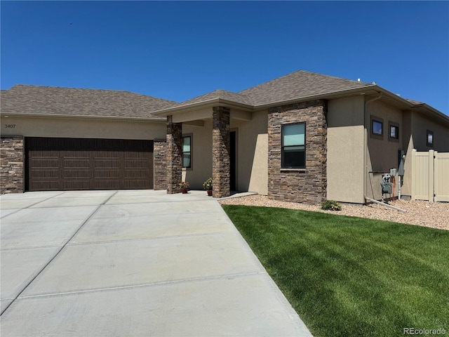 prairie-style home with a garage, stone siding, a front yard, and stucco siding