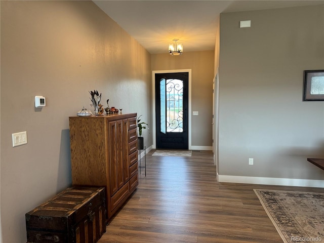 foyer featuring an inviting chandelier, baseboards, and dark wood-type flooring