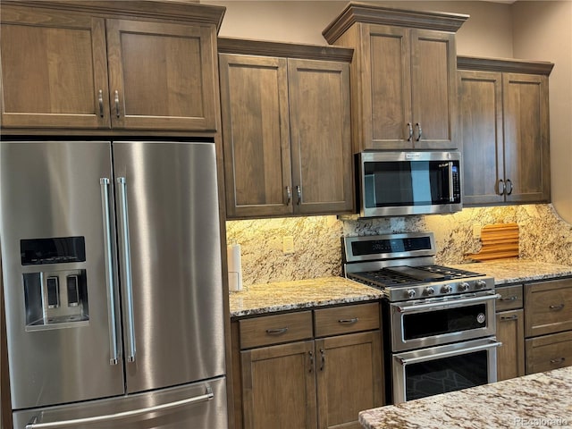 kitchen with stainless steel appliances, light stone counters, and tasteful backsplash